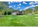Expansive backyard with a lush lawn, mature trees, and a charming home exterior with a deck at 1310 Dillon Rd, Austell, GA 30168