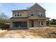 Two-story home with brick and siding exterior, open garage, and covered porch, in mid-construction phase at 206 Wild Ginger Bend, Woodstock, GA 30188