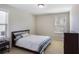 Cozy bedroom with a bed, side table, and a dresser, illuminated by natural light at 8605 Gladden Ln, Suwanee, GA 30024