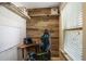 Compact office space featuring a desk, gaming chair, rustic wood wall, and natural light from the window at 8605 Gladden Ln, Suwanee, GA 30024