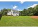 Expansive backyard featuring lush green grass, mature trees, and a charming white house at 765 Hembree Rd, Alpharetta, GA 30076