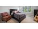 Comfortable bedroom features a dark wood bed frame, neutral walls, and a cozy reading chair at 765 Hembree Rd, Alpharetta, GA 30076