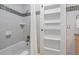 White bathroom with neutral tile, tub and shelving at 28 Peachtree Hills Ne Ave, Atlanta, GA 30305