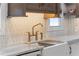 Close-up of a white farmhouse sink, quartz countertops, and a stylish faucet in a modern kitchen at 28 Peachtree Hills Ne Ave, Atlanta, GA 30305