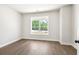 Simple and clean bedroom features a large window providing natural light and dark hardwood floors at 897 Porches Way, Dacula, GA 30019