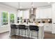 Modern kitchen featuring a center island with seating, sleek black stools, and bright natural light from the windows at 897 Porches Way, Dacula, GA 30019