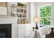 Elegant living room featuring built-in shelving around a fireplace, a large window, and stylish decor at 897 Porches Way, Dacula, GA 30019