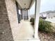 Side view of the front porch with brick and white pillars, with green bushes along the side at 4030 Rockcap Cv, Buford, GA 30519