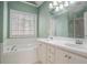 Bathroom with dual sinks, white cabinetry, and tub under the window at 190 The Falls Blvd, Covington, GA 30016