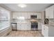Modern kitchen featuring white cabinetry, stainless steel appliances, and light wood flooring at 3265 Newcastle Way, Snellville, GA 30039