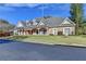 Exterior shot of the home, featuring its brick facade, manicured lawn, and well-maintained landscaping at 6000 E Andechs Smt, Johns Creek, GA 30097