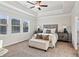 This carpeted main bedroom features a tray ceiling, ceiling fan, and bench at the foot of the bed at 2759 Porches Ln, Dacula, GA 30019