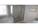 Tiled bathroom featuring a glass-enclosed shower, soaking tub, and a sunny window at 5315 Austrian Pine Ct, Cumming, GA 30040