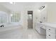 Well-lit bathroom features a soaking tub, white cabinets, and tile flooring at 4711 Oakleigh Manor Dr, Powder Springs, GA 30127