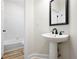 A half bathroom features a pedestal sink, a decorative mirror, and wood-look floors at 4711 Oakleigh Manor Dr, Powder Springs, GA 30127