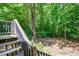 Secluded backyard featuring mature trees and deck access via wooden stairs at 5730 Paces Pl, Suwanee, GA 30024