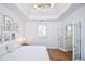 This main bedroom features a tray ceiling, modern light fixture and French doors leading to the ensuite bathroom at 5730 Paces Pl, Suwanee, GA 30024