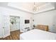 This main bedroom features a tray ceiling, modern light fixture, crib and French doors leading to the ensuite bathroom at 5730 Paces Pl, Suwanee, GA 30024