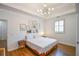 This main bedroom features a tray ceiling, modern light fixture and artwork above the headboard at 5730 Paces Pl, Suwanee, GA 30024