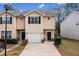 Two-story townhome features a one-car garage, well-kept lawn, and a neatly paved driveway at 2322 Coach Way, Jonesboro, GA 30236