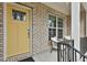 Inviting front porch with a yellow door, brick facade, and seating area at 135 Eastmark Way, Fayetteville, GA 30214
