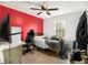 This bedroom includes a red accent wall, a ceiling fan, a window, a bed, and a gaming chair at 620 Bell Se Rd, Conyers, GA 30094