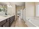 Bathroom featuring a dual sink vanity, soaking tub, tile floors, and access to the bedroom at 4012 Grand Park Ne Dr, Suwanee, GA 30024