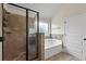 Modern bathroom featuring a tile shower with glass door and a soaking tub under a window at 4249 Caveat Ct, Fairburn, GA 30213