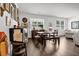 A dining room features wood floors, natural light from windows, and a dark wood dining table with chairs and a bench at 1991 Vidalia Ct, Dacula, GA 30019