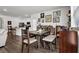 A dining room features a dark wood dining table and bench, light hardwood floors, and galley-style kitchen in the background at 1991 Vidalia Ct, Dacula, GA 30019
