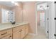 Bathroom with double vanity, beige cabinets and neutral tile, leading to a closet and hallway at 1439 Mill Pointe Ct, Lawrenceville, GA 30043