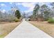 Long concrete driveway leading to a single-story home with gray siding and an attached two-car garage at 1925 Emerald Dr, Cumming, GA 30040