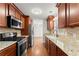Galley kitchen featuring granite counters, stainless steel appliances, tile backsplash and wood cabinets at 1925 Emerald Dr, Cumming, GA 30040