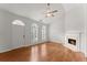Bright living room with hardwood floors, a fireplace, ceiling fan, and arched windows with shutters at 1925 Emerald Dr, Cumming, GA 30040