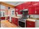 Bright kitchen with stainless steel appliances, red cabinets, and unique tile backsplash, complemented by terra cotta tile flooring at 1175 Kingsley Ne Cir, Atlanta, GA 30324