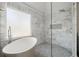 Bathroom featuring soaking tub, frameless glass shower, marble walls, and rainfall shower head at 130 Cauley Club Ct, Johns Creek, GA 30097