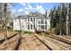 Rear exterior view of a two-story home with a deck, large windows, and mature trees at 130 Cauley Club Ct, Johns Creek, GA 30097
