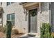 Welcoming gray front door of a light brick townhome, complete with a wreath and manicured bushes at 4358 White Spruce Aly, Doraville, GA 30360