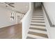 Open-concept living and dining spaces lead to a staircase with light hardwood steps and a white wood railing at 108 Black Gum Unit 38 Ln, Auburn, GA 30011