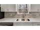 Close-up of a kitchen sink featuring quartz countertop, stainless fixtures, and sleek tile backsplash at 2216 Marbut Farms Trce, Lithonia, GA 30058