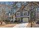 Charming two-story home with blue siding, white trim, and an attached garage against a wooded backdrop at 2111 Glenwood Downs Dr, Decatur, GA 30035
