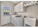 Well-lit laundry room with washer, dryer, utility sink, and ample storage cabinets at 113 Brianna Way, Woodstock, GA 30188