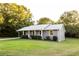 Exterior view of gray brick home with manicured hedges, a covered porch, and a well-kept lawn at 391 Oak Dr, Social Circle, GA 30025