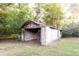 Backyard shed with cinder block wall and weathered wood, surrounded by green grass and trees at 391 Oak Dr, Social Circle, GA 30025