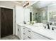 Bright bathroom featuring double sink vanity with white cabinetry, black hardware and marble tile flooring at 105 Crown Ln, Woodstock, GA 30188