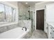 Bright bathroom featuring a soaking tub, glass-enclosed shower with marble tile, and a barn door at 105 Crown Ln, Woodstock, GA 30188