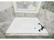 Bright bathroom featuring a soaking tub with marble tile surround and a window with natural light at 105 Crown Ln, Woodstock, GA 30188