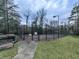 Fenced tennis court with lighting and a nearby bench at 6700 Roswell Rd # 24E, Atlanta, GA 30328