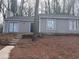A gray single-story home featuring a black front door, white trim, and steps leading to the entrance at 5073 Martins Crossing Rd, Stone Mountain, GA 30088