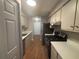 Galley kitchen with stainless steel appliances, light-colored cabinets, and a view towards the front door at 5073 Martins Crossing Rd, Stone Mountain, GA 30088